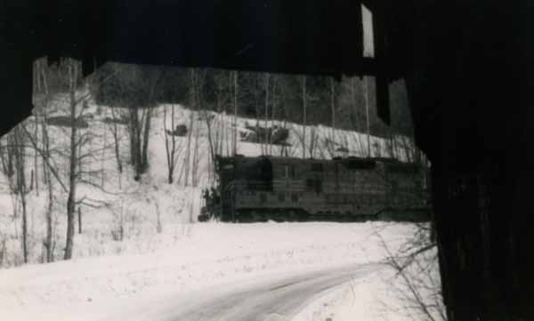 Maine Central Railroad train passes by a covered bridge